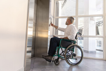 Male entrepreneur with disabilities in wheel chair waiting for elevator in office