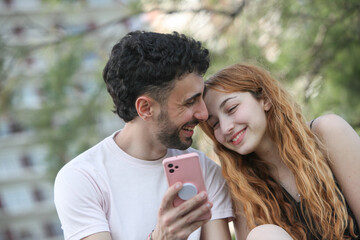 cute young loving couple using smartphone at the park