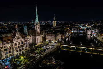 Obraz premium Beautiful aerial view of the city of Zurich in Switzerland at night - the Limmat River and its iconic churches, buildings rivers and Clocks.