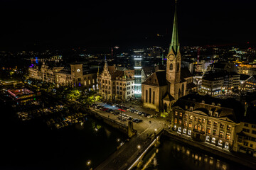 Beautiful aerial view of the city of Zurich in Switzerland at night - the Limmat River and its iconic churches, buildings rivers and Clocks.