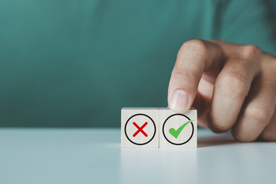 Regulatory compliance, project feasibility concept. Businessman chooses wooden block with approval mark, approve or reject business proposal. Do and don't or like and unlike with positive and negative