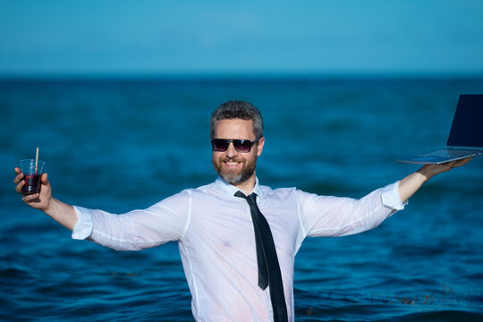 Fun business lifestyle. Freelance work, distance online work, e-working. Summer business. Business man in shirt remote working on laptop in sea water. Business man working online.