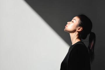 Obraz premium An Asian woman stands gracefully in a minimalist outfit, thoughtfully reflecting in a contrast of light and shadow. Generative AI