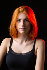 Cute red-haired girl, studio portrait on a black background.