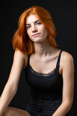 Fototapeta premium Cute red-haired girl, studio portrait on a black background.