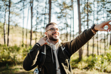 Young caucasian man hiking or trekking through the forest	