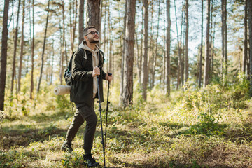 Young caucasian man hiking or trekking through the forest	