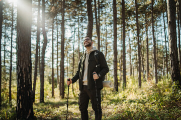Fototapeta premium Young caucasian man hiking or trekking through the forest 