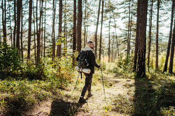 Obraz premium Young caucasian man hiking or trekking through the forest 