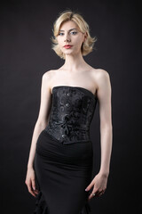 Fototapeta premium Expressive young blonde under a bob in the studio. In a black corset and dress.