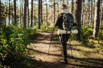 Young caucasian man hiking or trekking through the forest	