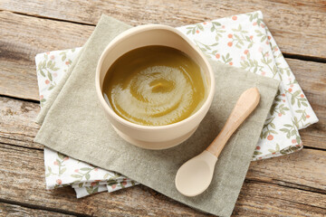 Delicious baby food in bowl with spoon on wooden table