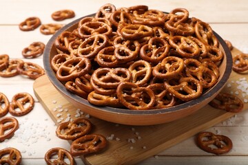 Tasty pretzel crackers with salt on light wooden table, closeup