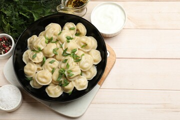 Delicious pelmeni with green onion served on wooden table, flat lay. Space for text