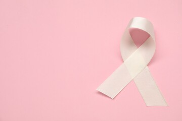 White awareness ribbon on pink background, top view. Space for text
