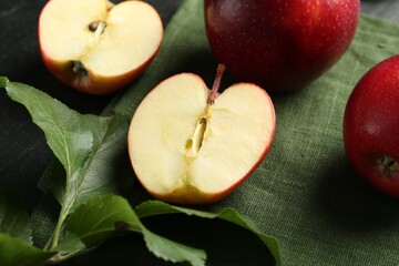 Fresh ripe red apples and green leaves on grey table, closeup