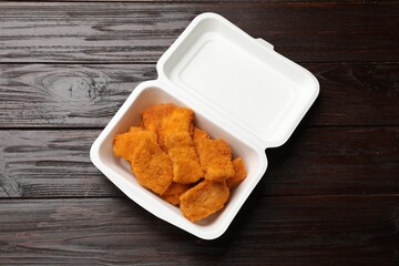 Tasty chicken nuggets on wooden table, top view