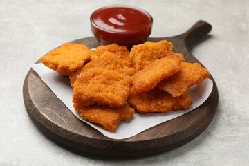 Delicious chicken nuggets with ketchup on grey textured table, closeup