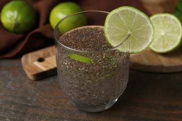 Glass of drink with chia seeds and lime on wooden table, closeup