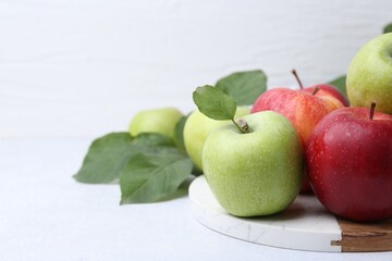 Fresh ripe apples and green leaves on light grey table. Space for text