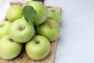 Fresh ripe green apples on white tiled table, closeup. Space for text