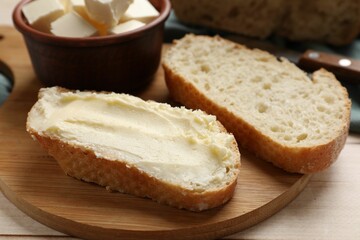 Fresh bread with butter on light wooden table, closeup