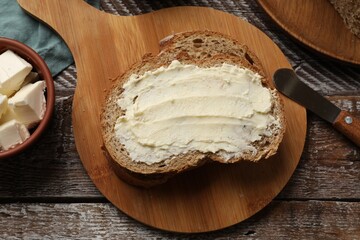 Fresh bread with butter and knife on wooden table, flat lay