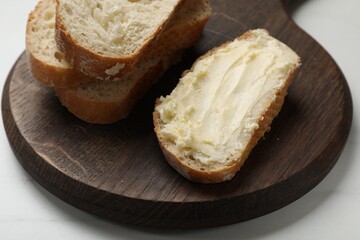 Fresh bread with butter on white table, closeup