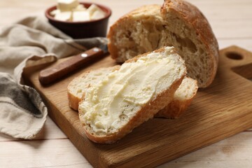 Fresh bread with butter on light wooden table, closeup