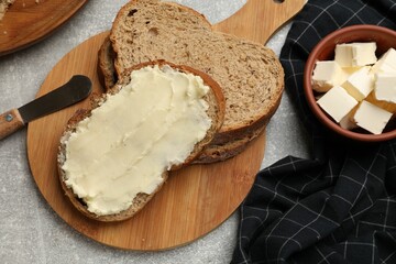 Fresh bread with butter and knife on grey table, flat lay