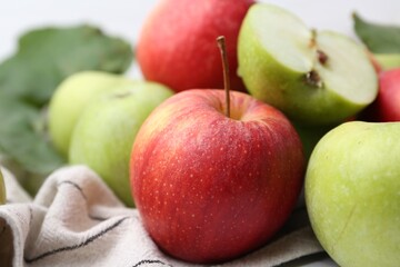 Different ripe whole and cut apples on towel, closeup