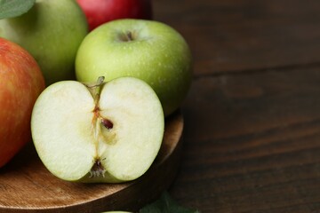 Different ripe apples on wooden table, closeup. Space for text