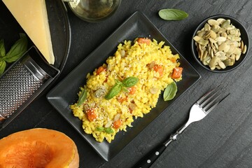 Delicious pumpkin risotto served on black table, flat lay