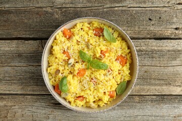 Delicious pumpkin risotto in bowl on wooden table, top view
