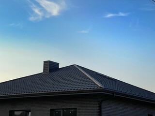 Roof and chimney. The roof is made of black metal tiles. Four-pitched roof