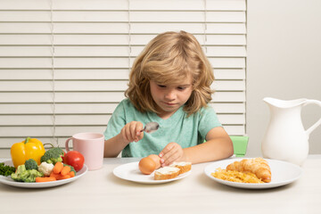 Kid eating egg. Portrait of child eat fresh healthy food in kitchen at home. Kid boy eating breakfast before school.