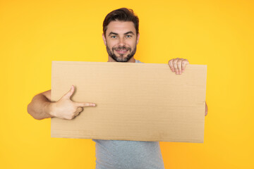 Handsome man holding empty board and pointing finger on board. Guy showing blank board with copyspace. Idea and offer. Your advertisement. Blank advertising board with empty space for text, mockup.