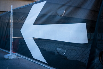 Large canvas sign with a bold white arrow on a black background direction for pedestrians.