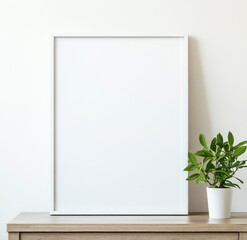 A large white poster frame sits atop an empty wooden dresser, a small plant beside it.  