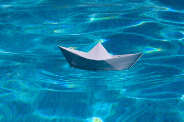 Fototapeta premium Sailing yacht concept, paper ship with sailing boat. Paper boat into water. Concept of tourism, travel dreams vacation holiday, dreaming traveling, sailing adventure.