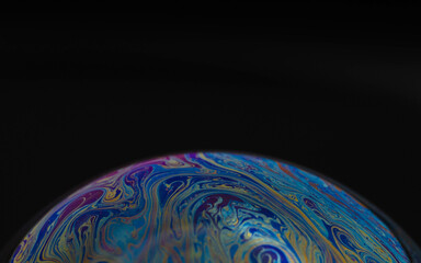 macro drawing of the earth on a hemisphere in a soap bubble on a black background, empty space for an inscription, ecology