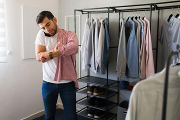 Business man multitasking in his walk-in closet: checking the time, talking on the phone, and getting dressed