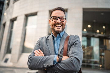 Fototapeta premium Portrait of man businessman stand with arm crossed in front building