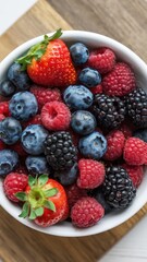 White bowl with fresh raspberries and blueberries, close-up top view