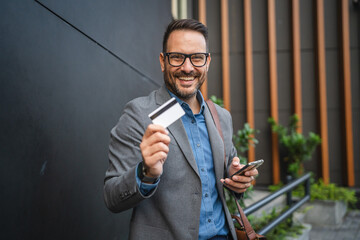 Portrait of adult businessman stand with mobile phone and credit card