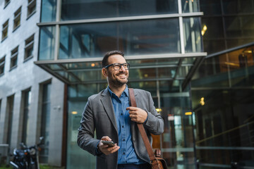 Fototapeta premium Adult man businessman use mobile phone in front modern buildings