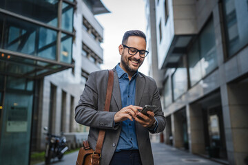 Adult man businessman use mobile phone in front modern buildings