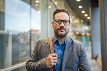 Portrait of businessman with briefcase walk around modern buildings