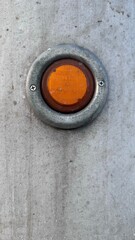 Amber-colored signal light bulb. Dimensional lights on the sidewall of an American truck. Metal texture with tains. Compliance with safety precautions.