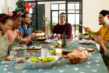 Multiracial friends celebrating christmas dinner together, at home